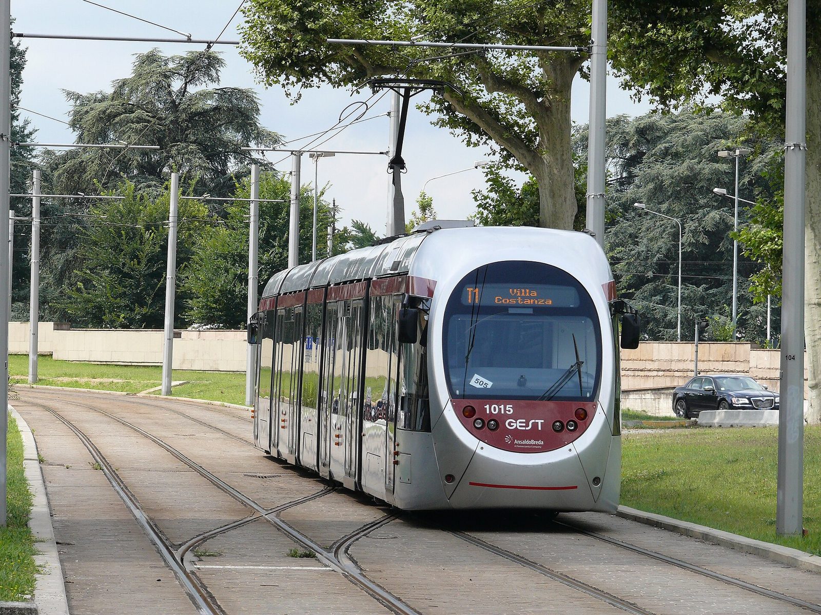Un tram argentato della tramvia di Firenze, con l'indicazione Villa Costanza sul display, percorre un tratto di binari tra prati e grandi alberi